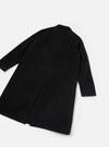 Black Mowbray Mac Coat laid flat on a light grey surface, shot from above at an angle showing the back. The smooth, matte fabric has a clean, unbroken back panel with a centre vent at the hem. A notched collar is visible at the top. Long sleeves with plain cuffs extend to the sides.