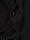 Close-up detail of the black Mowbray Mac Coat's button placket, showing two four-hole dark brown buttons against a soft, lightly textured wool-blend fabric. The front opening is partially open, revealing a dark woven lining with topstitched facing edges visible along the placket.