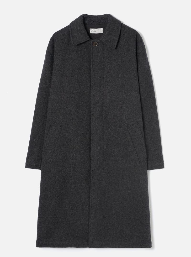 Grey marl wool overcoat laid flat on a light grey seamless backdrop. Features a point collar, concealed fly front with a single visible dark button at the neck, two large patch pockets at the lower front, and long plain sleeves. The coat reaches below the knee in a relaxed silhouette. Fabric has a soft, lightly flecked marl texture.