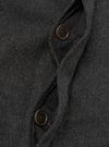 Close-up of the grey marl wool-blend fabric on a Mowbray Mac Coat, showing two dark brown four-hole buttons on the front placket. The coat is open, revealing a dark woven lining. Topstitching runs along the inner facing edge. The brushed, flecked texture of the outer fabric is clearly visible.