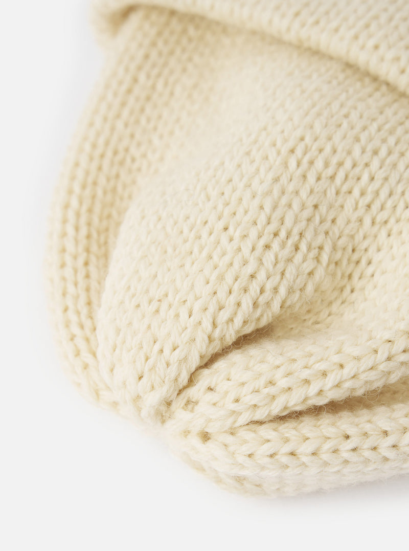 A detailed close-up shot of the Ecru British Wool Short Watch Cap against a plain background, emphasizing the off-white British wool material, ribbed weave, and pinched crown structure.