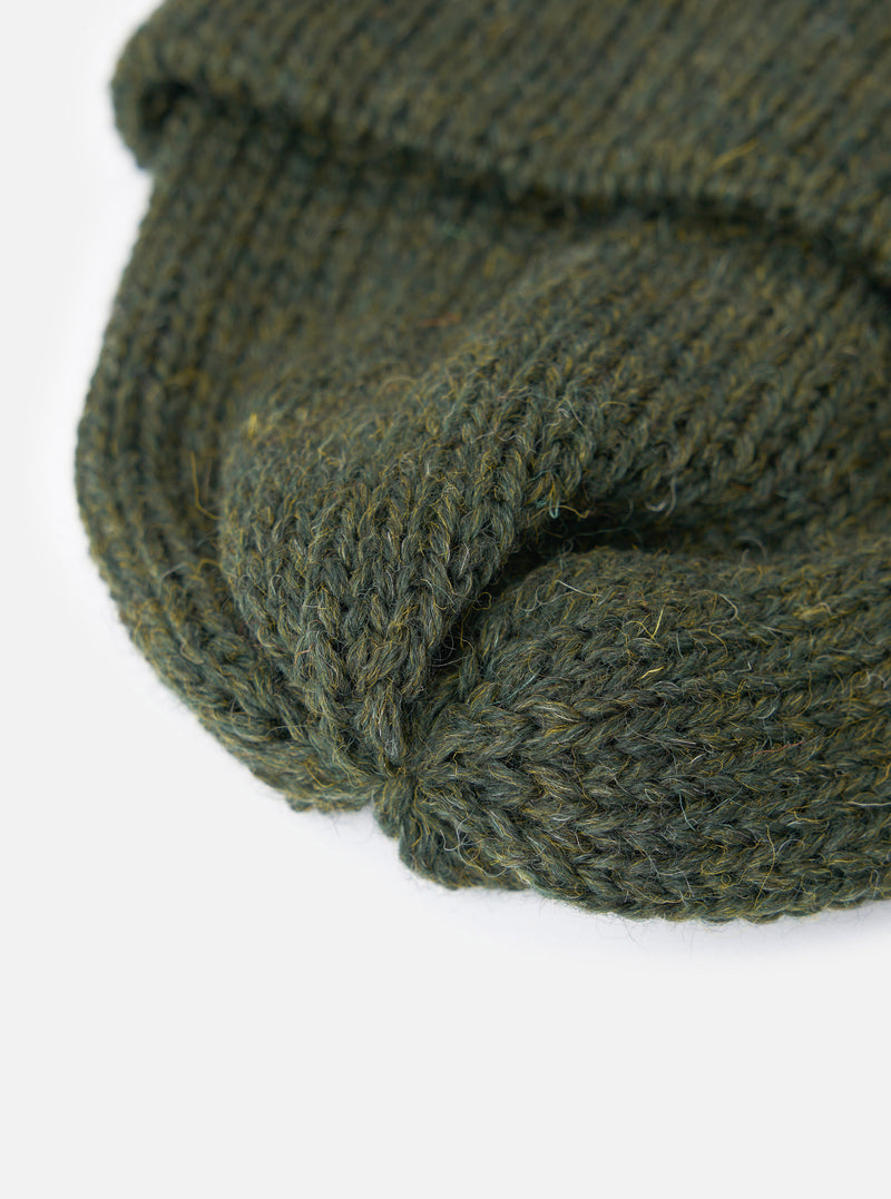 A close-up view of the Olive British Wool Short Watch Cap on a plain background, highlighting the dark green 100% British wool yarn, 5-gauge rib construction, and pinched crown detail.