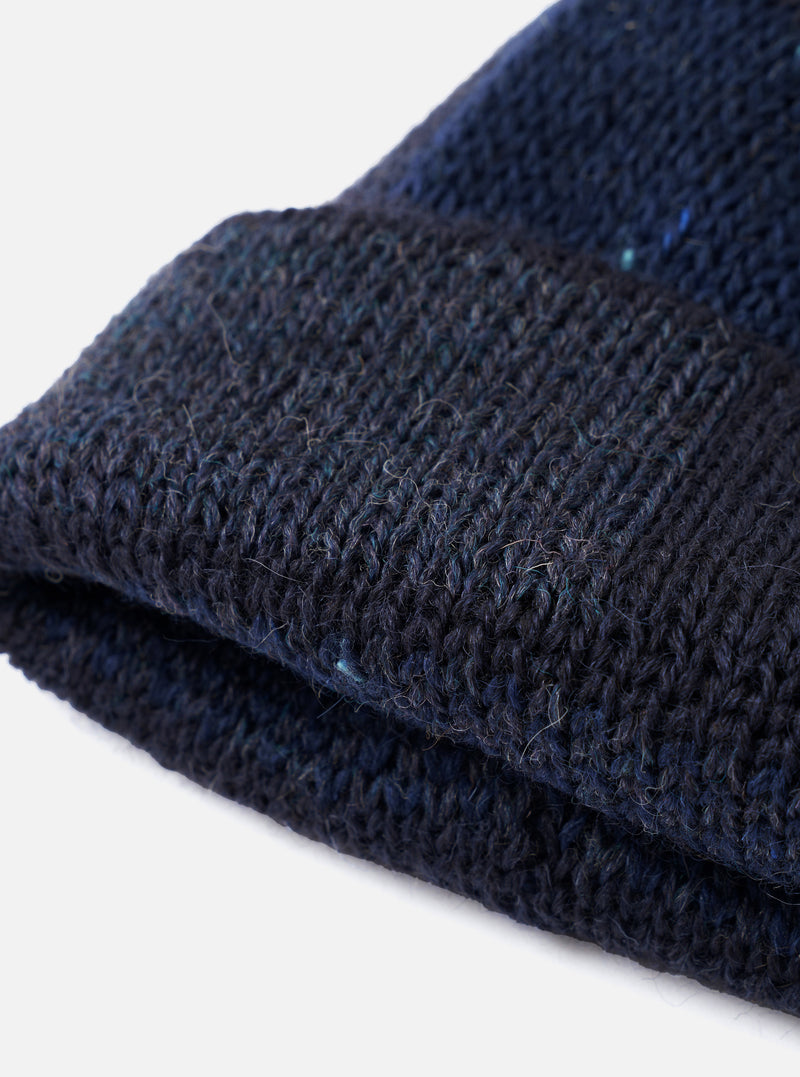 An alternate side angle of the Navy British Wool Short Watch Cap set against a neutral backdrop. The deep navy blue wool beanie showcases a compact turned-up cuff and tight ribbed knitting.