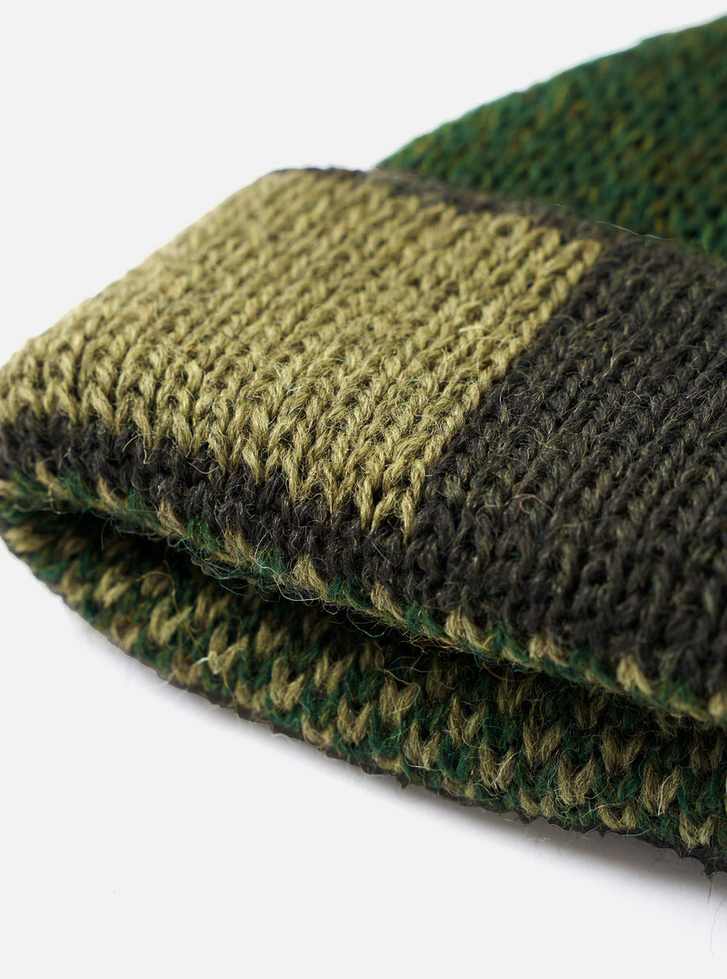 An alternate view of the Patched Olive British Wool Short Watch Cap against a plain studio background. The short knitted watch cap highlights the olive wool texture, ribbed design, and patch embellishment.