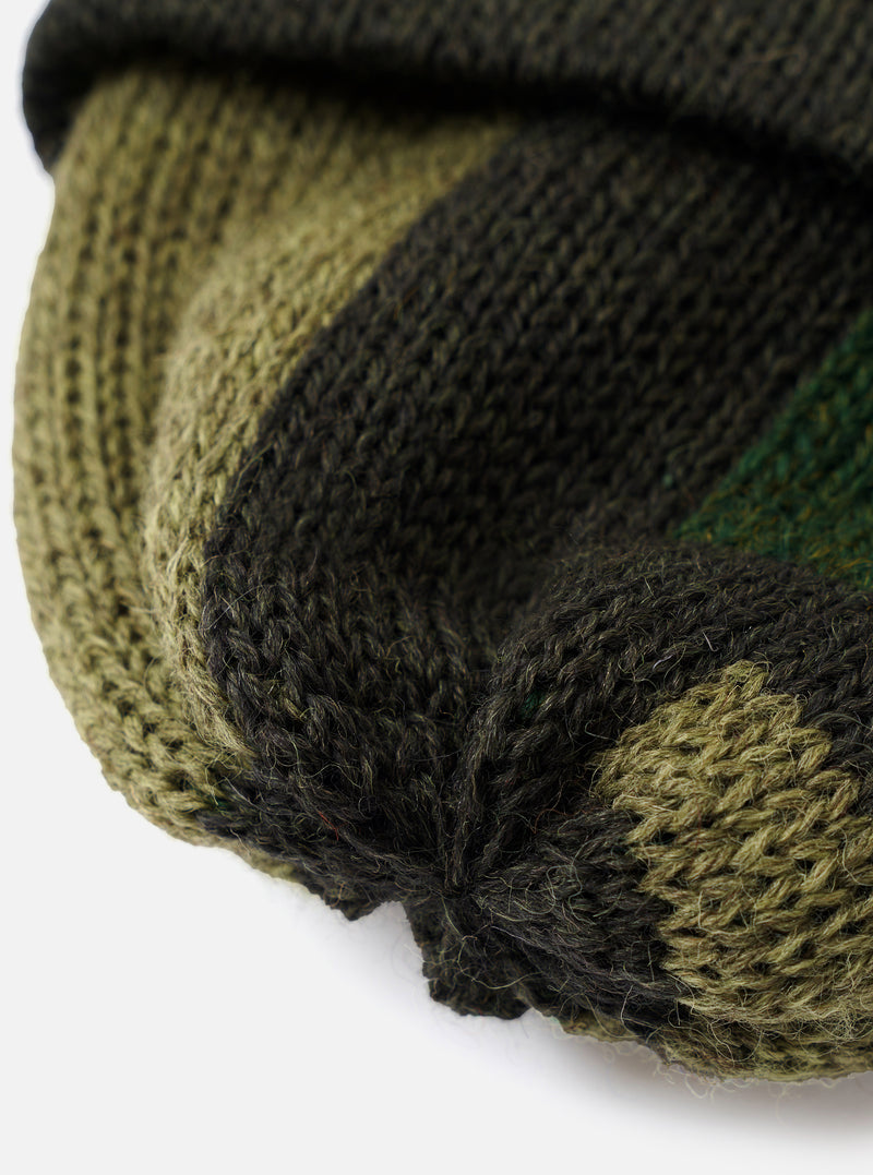 A detailed close-up shot of the Patched Olive British Wool Short Watch Cap on a plain light background, showing the fine rib-knit structure, olive green wool finish, and patch detailing up close.