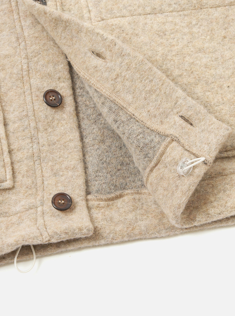 A close-up detail image of the Fawn Wool Fleece Advance Cardigan against a light background, focusing on the button-front placket, fine edge binding, patch pocket, and soft fawn fleece fabric structure.