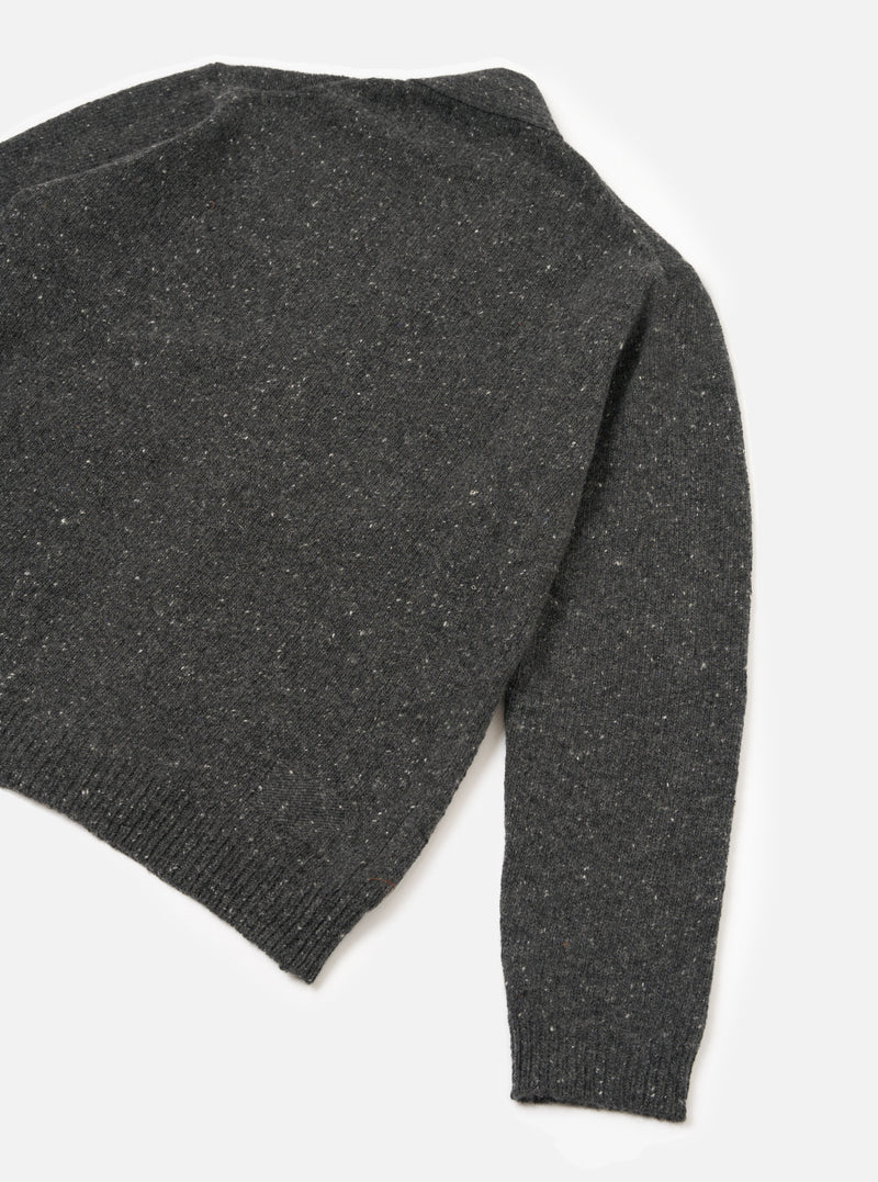 A male model viewed from the rear wearing the Black Wool Fleck Langdale Cardigan against a plain white studio backdrop, highlighting the loose fit silhouette and textured black yarn with subtle flecked detail.