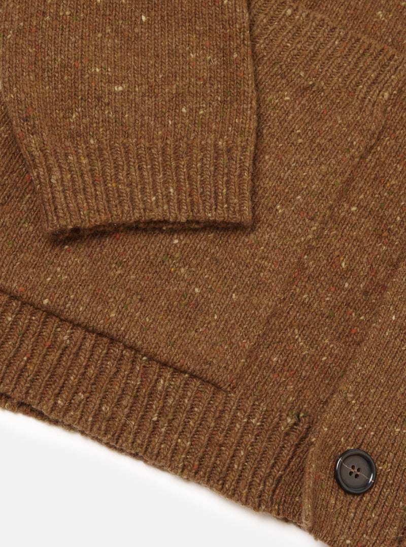A close-up image of a model wearing the Brown Wool Fleck Langdale Cardigan against a plain backdrop, focusing on the buttoned front, front patch pocket, V-neck collar, and detailed speckle pattern in the yarn.