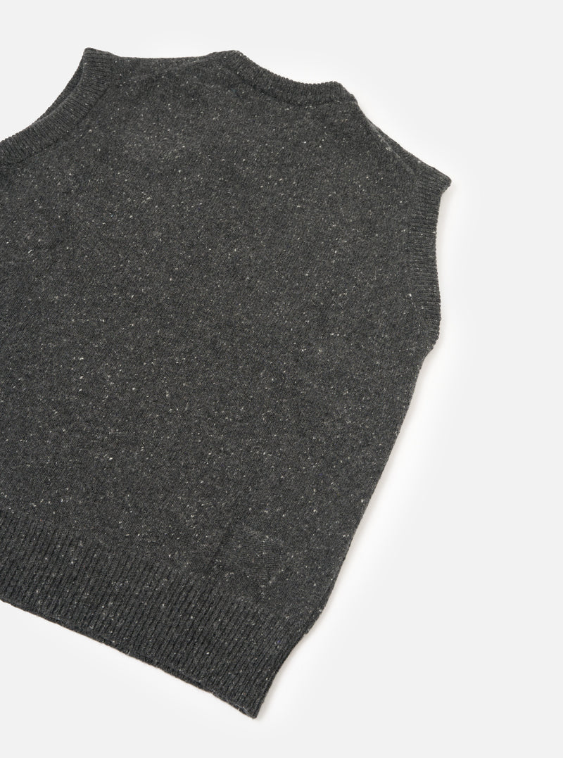A side profile view of a model wearing the Black Wool Fleck Sweater Vest on a plain background, highlighting the sleeveless cut, neat armhole finishing, and textured dark fleece-flecked knit.