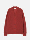 Deep orange alpaca knit cardigan laid flat on a light grey studio backdrop. V-neckline with a woven Universal Works label at the back neck. Five dark brown buttons run down the centre front. Raglan sleeves with ribbed cuffs and a ribbed hem. Soft, fluffy knit texture throughout.
