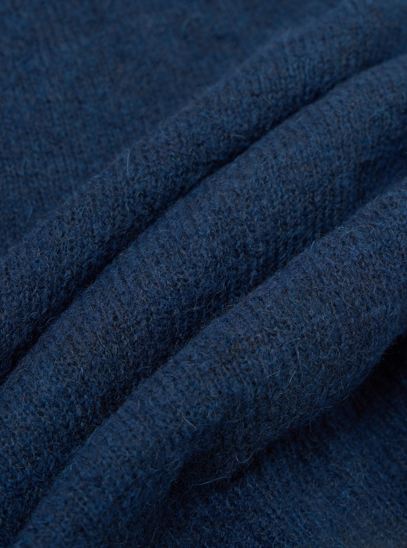 Close-up detail of the navy alpaca knit fabric of the David Cardigan, showing soft, slightly hairy fibres and a textured knit structure. The fabric is gathered into deep folds, highlighting its weight and warmth. Shot against a plain white studio background.