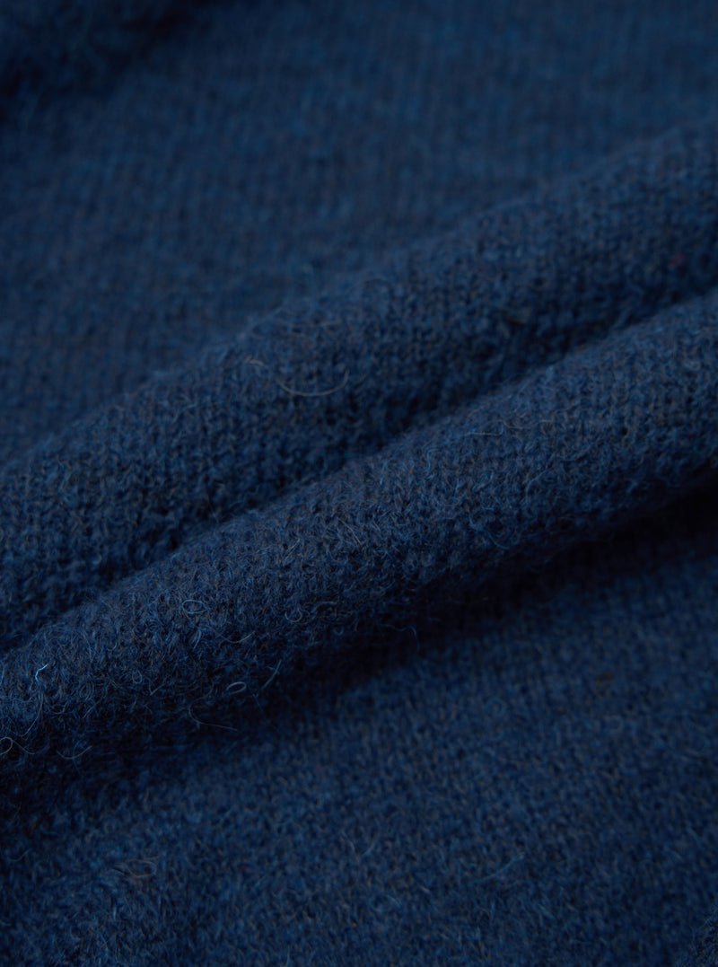 Close-up detail shot of the navy alpaca knit fabric, showing a soft, slightly hairy texture with a fine knit construction. The deep blue-navy yarn has subtle tonal variation. The fabric is loosely folded to show its depth and loft. No background is visible.