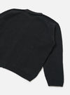 Black ribbed-knit eco wool zip cardigan, flat lay on a white studio backdrop. Close-up rear angle showing the back panel, one full sleeve, and ribbed hem. Chunky vertical rib texture throughout, with a ribbed cuff and a ribbed collar visible at the top edge.