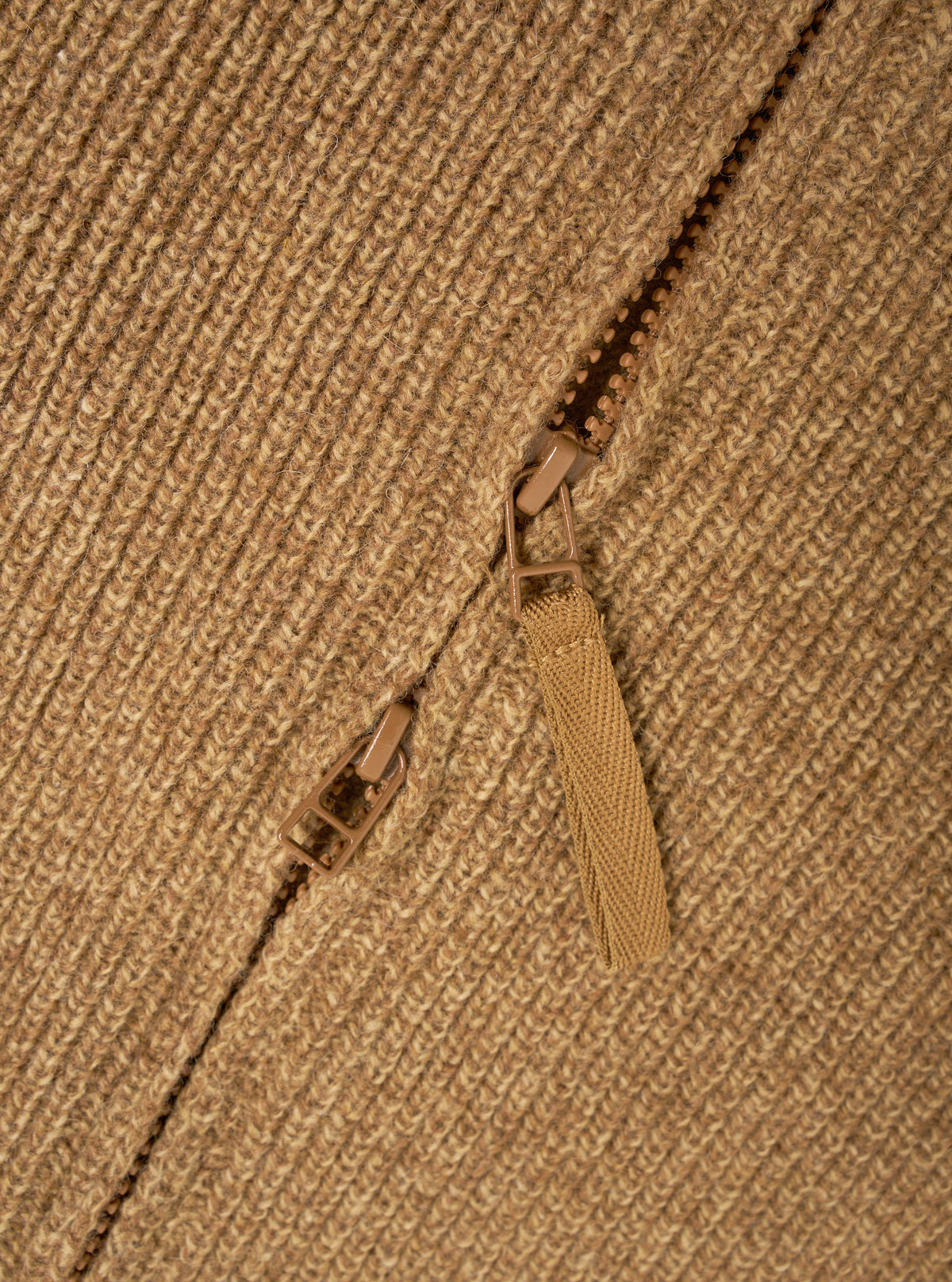 A close-up detail shot of the Tawny Eco Wool Zip Cardigan against a plain white studio background. The image highlights the rich tawny brown eco wool knit fabric, zipper hardware, and detailed collar stitch construction.