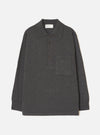 Charcoal merino knit pullover shirt laid flat on a light grey seamless backdrop. Features a wide point collar, four-button placket with dark buttons, a left chest patch pocket, long sleeves with ribbed cuffs, and a ribbed hem. Fine smooth knit texture throughout. Universal Works woven label at back neck.