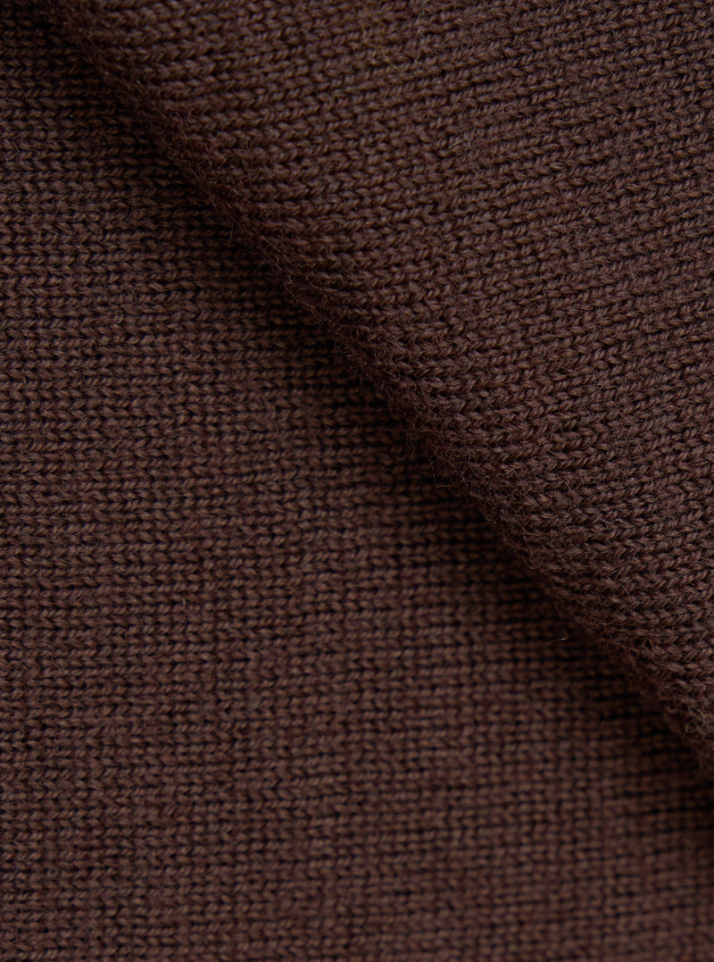 Close-up detail shot of the espresso brown merino knit fabric, showing a uniform stocking stitch construction with a slightly heathered texture. The fabric is gathered and folded to highlight the knit structure and drape. No background is visible.