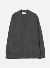 Charcoal merino cardigan laid flat on a light grey seamless backdrop. V-neckline with a woven Universal Works label inside. Four dark horn-effect buttons run down the front placket. Two patch pockets sit at the lower front. Ribbed cuffs and hem. Fine, smooth knit texture throughout. Full length, unbutoned view from the front.