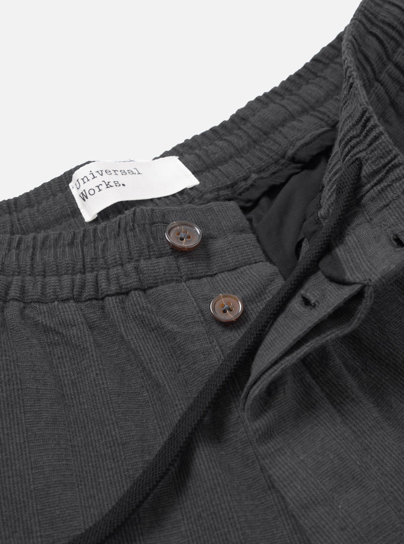 A detailed close-up shot of the waist area of the Grey Liverpool Check Oxford Pant on a solid white background, highlighting the drawstring closure, pleated waist construction, and grey check cotton-linen textile texture.