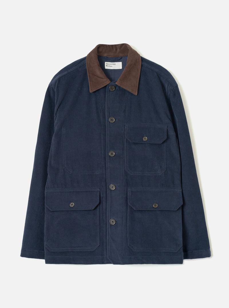 Dark navy corduroy utility jacket laid flat on a light grey studio backdrop. Features a contrast brown corduroy collar, five dark horn buttons at the front placket, two chest patch pockets with button flaps, and two larger patch pockets at the hip with button flaps. Woven brand label visible at the neck.