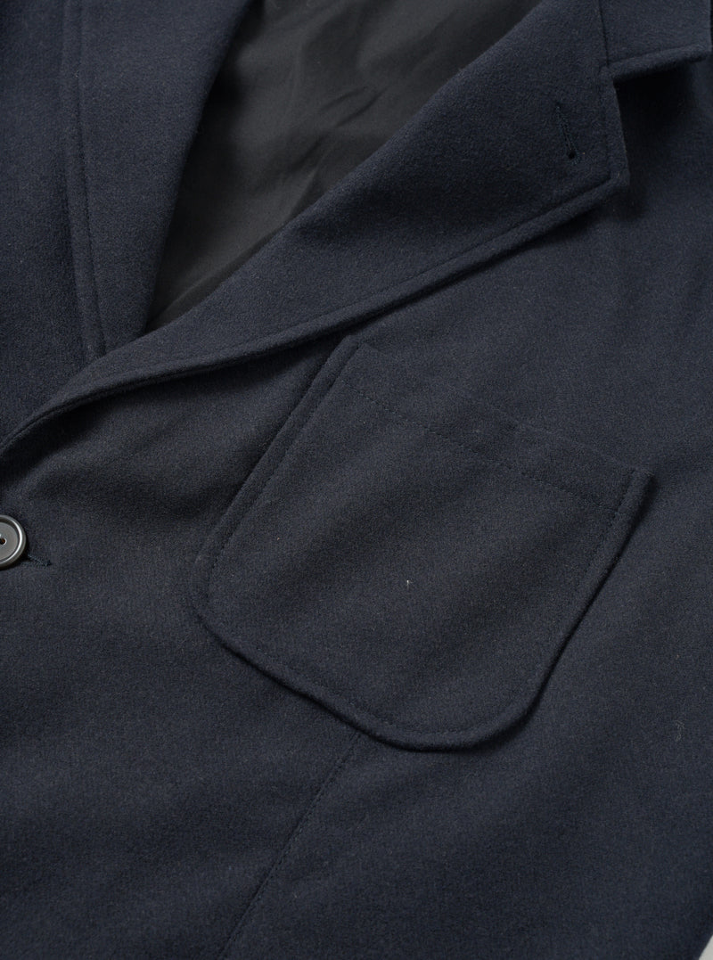 Angled side view of the Dark Navy Dublin Wool Mix Two Button Jacket worn by a model against a plain studio background. The photo focuses on the lapel roll, two-piece sleeve construction, and textured navy wool-blend cloth.