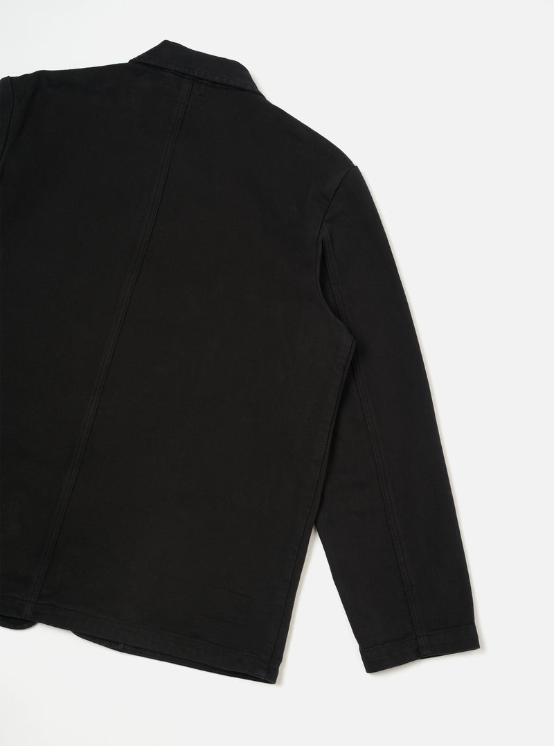 Back view of the Black Dexter Twill OG Bakers Chore Jacket displayed flat against a plain off-white background. The shot highlights the clean back paneling, shoulder seams, and durable black organic cotton twill construction.