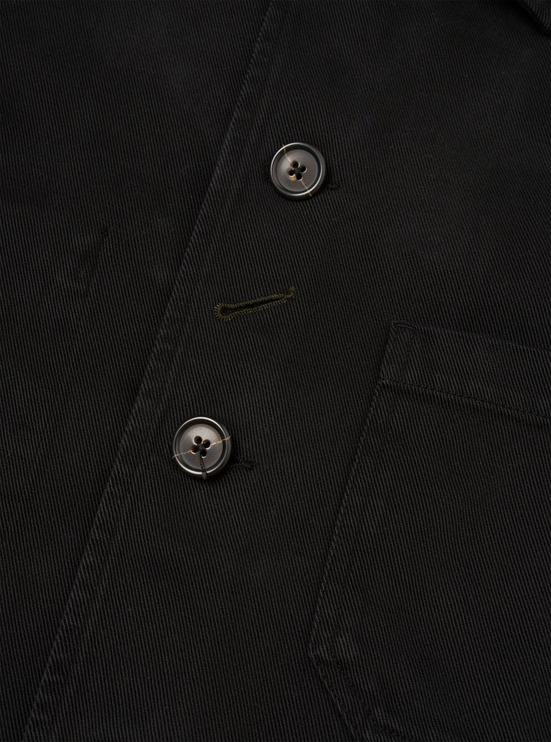 Close-up detail view of the Black Dexter Twill OG Bakers Chore Jacket against a plain white background. The image emphasizes the fine texture of the black organic cotton twill, button closure, and front patch pocket stitching.