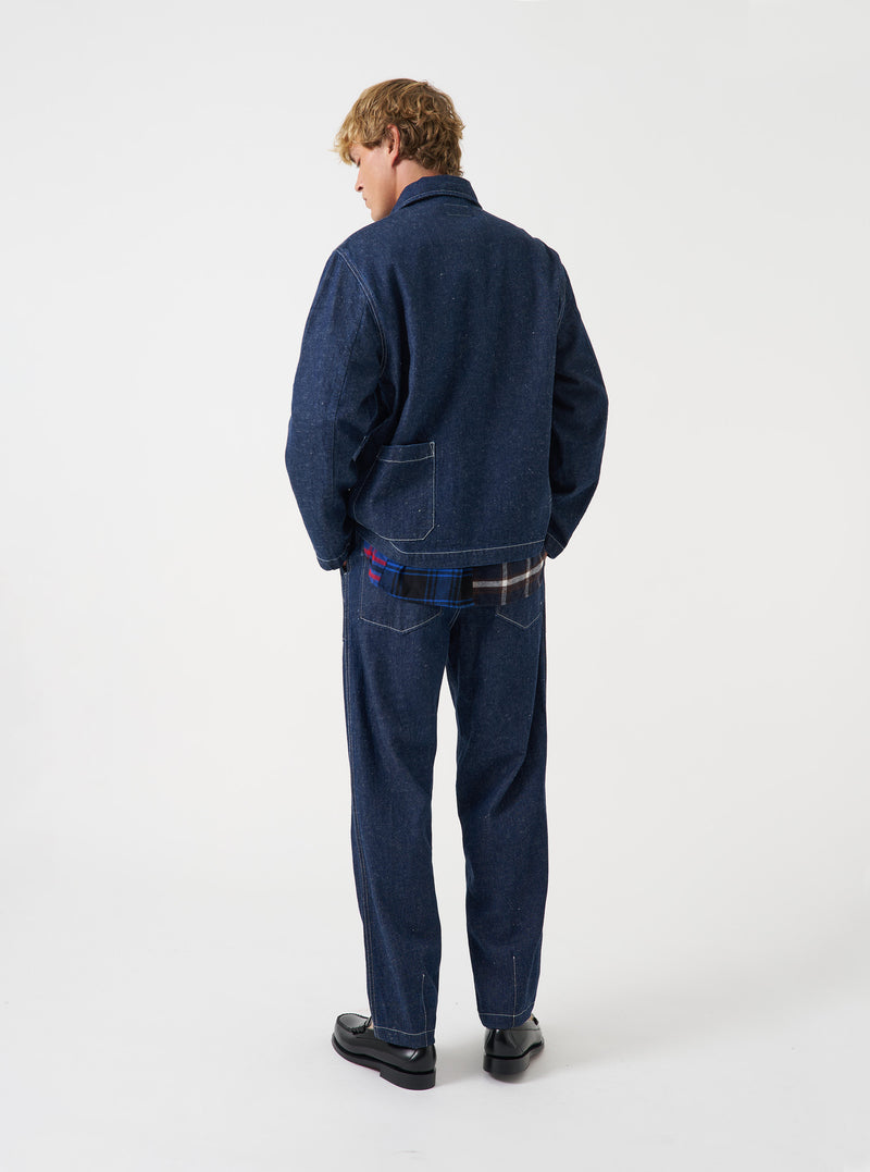 A male model wears the Indigo Future Denim Ives Jacket, posed against a plain off-white studio background. The shot highlights the rich indigo denim fabric, classic collar construction, utility chest pockets, and relaxed tailored fit.