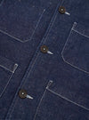 Close-up detail of the indigo Future Denim Ives Jacket, showing three dark horn buttons along the front placket and four large patch pockets with contrast white topstitching. The raw indigo denim texture is clearly visible. Shot flat on a plain white background.