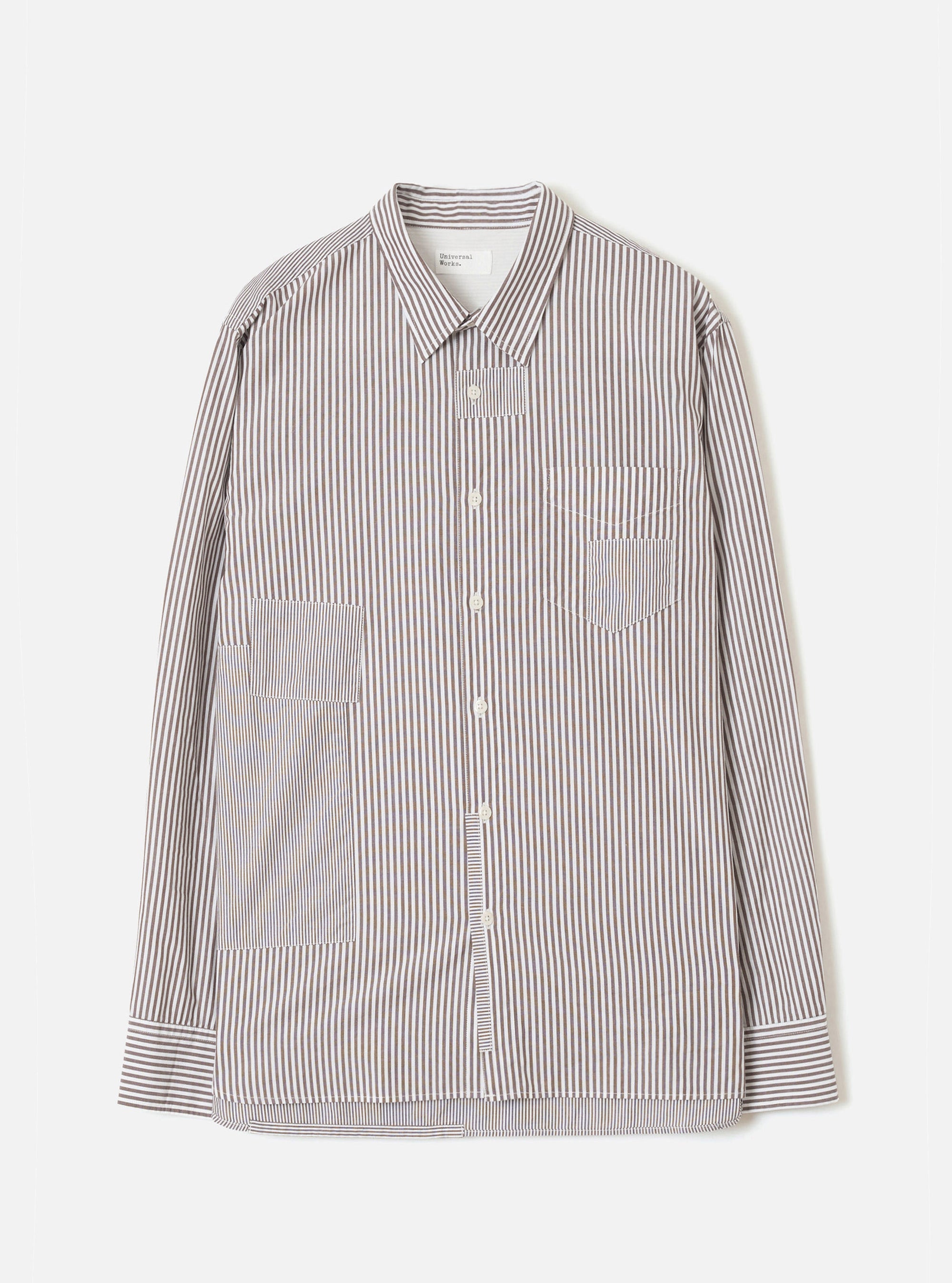 Brown and white vertical stripe cotton shirt, flat lay on a light grey backdrop. Point collar, front button placket with cream buttons, chest patch pocket, two large lower patch pockets, and button cuffs. Universal Works label visible at neck.