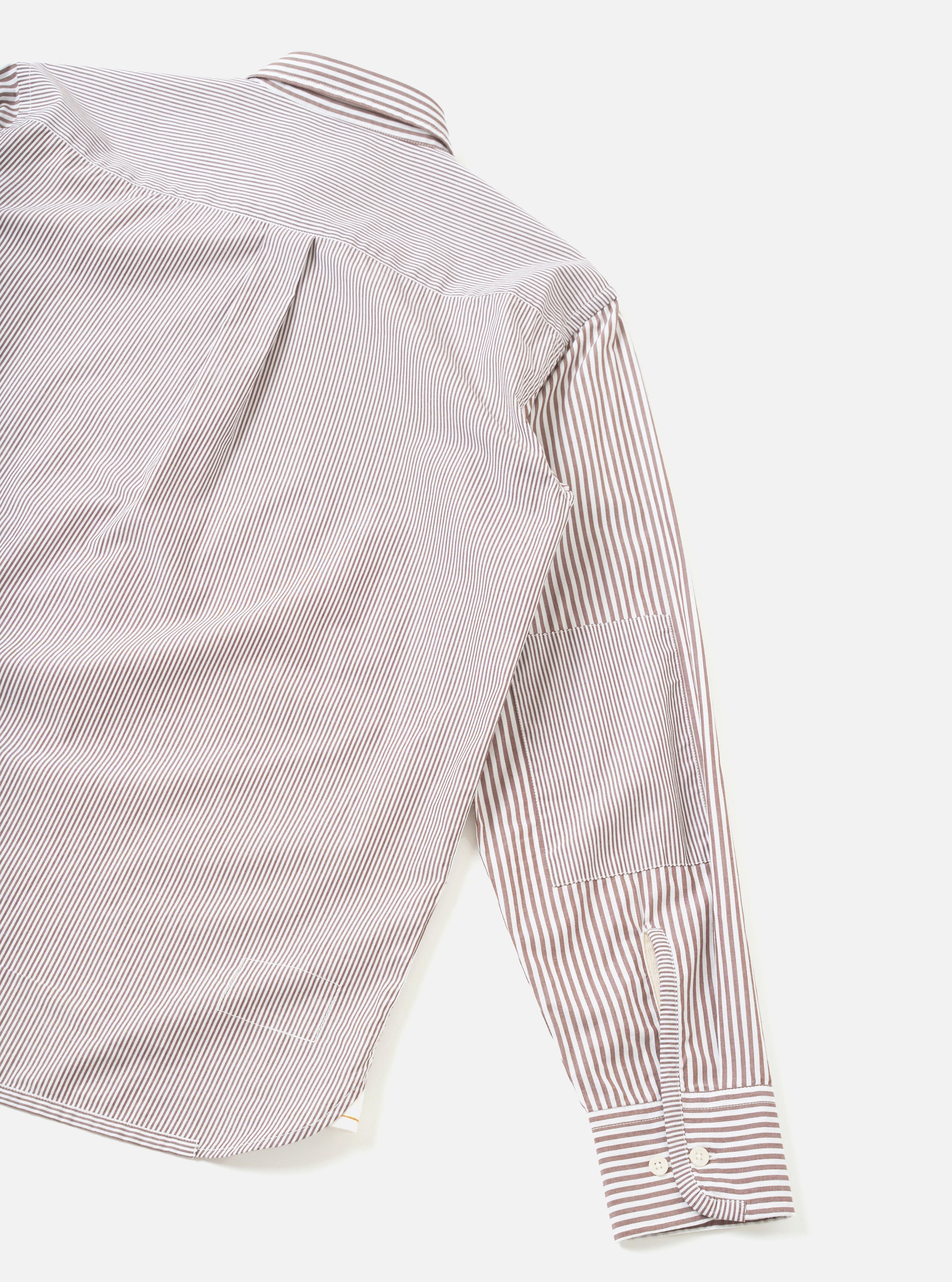 Brown and white fine-stripe cotton shirt laid flat on a white surface, shot from above at an angle. The back yoke, collar and one long sleeve are visible. The cuff features two white buttons and sits fully extended. Fabric has a crisp poplin texture.