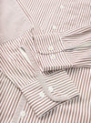 Close-up flat lay of the brown and white striped Queens Cotton Patched Shirt. The shot focuses on the cuffs and front placket. Both barrel cuffs feature white buttons, with additional buttons visible on the placket. Fine Bengal stripes run across a smooth cotton fabric.