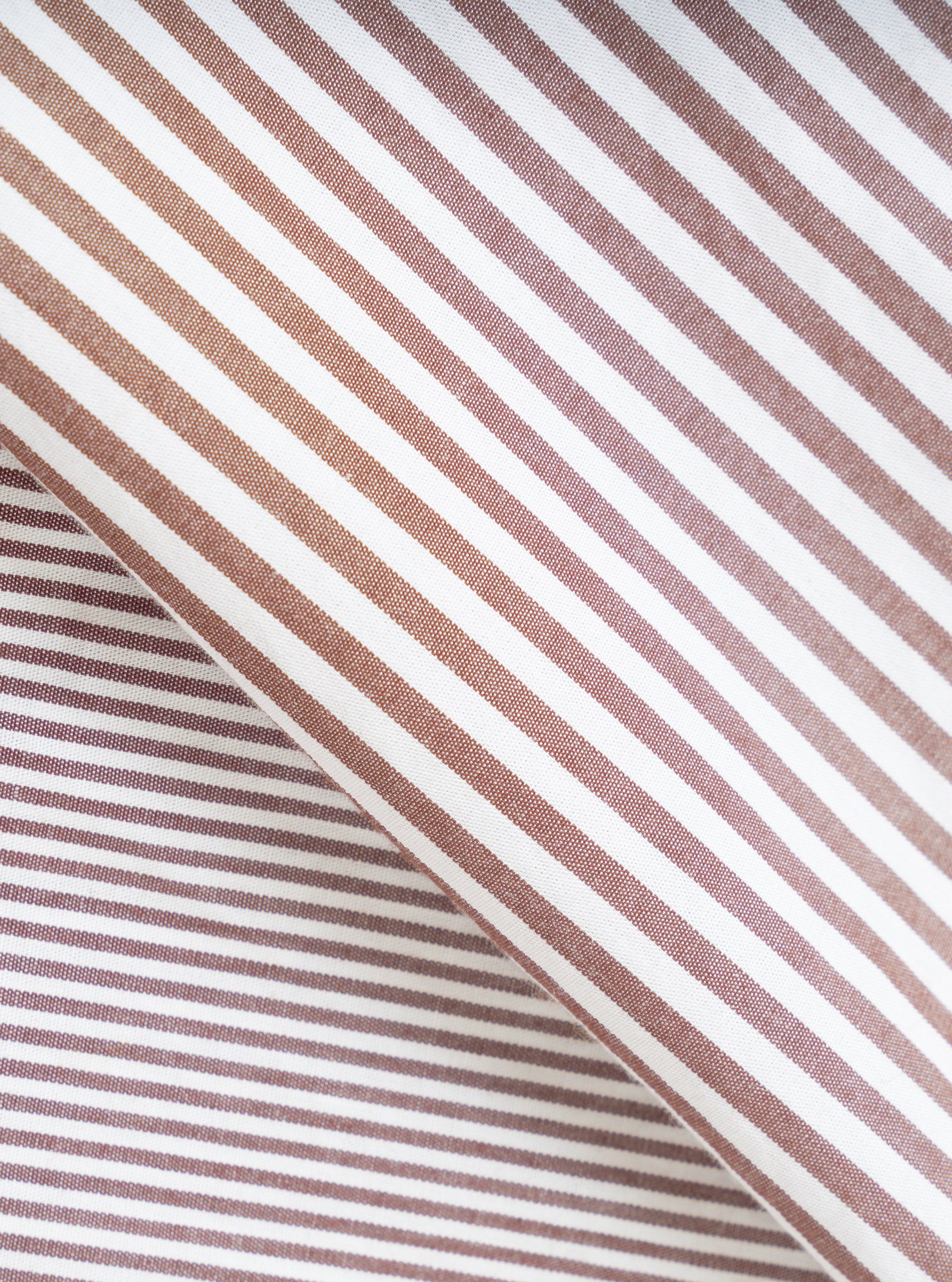 Close-up fabric detail of the brown Queens cotton patched shirt, showing a woven stripe pattern in alternating brown and white. The fabric is folded to reveal both the outer surface and an inner layer with narrower stripes, highlighting the cotton weave texture.