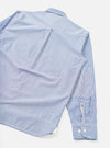 Navy and white fine-stripe cotton shirt laid flat on a white surface, shot from above at an angle. The back yoke and a centre pleat are visible. One sleeve extends to a buttoned barrel cuff with two white buttons. A small chest patch pocket is visible on the sleeve.