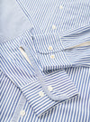 Close-up flat lay of a navy and white Bengal-stripe cotton shirt. Two barrel cuffs with white buttons are prominent, alongside a button placket with white buttons and a small chest patch pocket. The fabric has a crisp, smooth texture. No model or mannequin present.