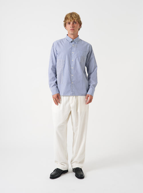 A male model wears the Navy Queens Cotton Patched Shirt buttoned up against a clean studio background. The full front shot highlights the button-down collar, patch pocket, and subtle striped patchwork pattern.