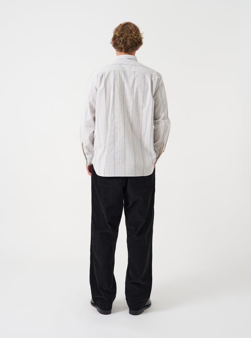 A male model wears the Dove Monk Organic Stripe Square Pocket Shirt in a back view shot against a neutral studio backdrop. The photo details the subtle striped fabric and clean rear silhouette of the shirt.