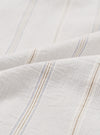 Close-up of the organic stripe fabric on the Dove Monk pocket shirt. The off-white woven cloth features fine vertical pinstripes in pale blue and tan, grouped into repeat stripe clusters. The soft, lightweight texture is visible across two folded layers of fabric against a white studio backdrop.