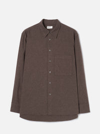 Brown brushed flannel shirt on a plain light grey studio backdrop, no model or mannequin. Features a point collar, five-button placket with dark buttons, one large patch pocket on the left chest, long sleeves with plain cuffs, and a curved hem. The fabric has a soft, matte flannel texture in a muted brown marl.
