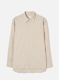 Ecru brushed flannel long-sleeve shirt laid flat on a light grey studio backdrop. Features a point collar, full button placket with tonal buttons, a single patch chest pocket on the left, buttoned cuffs, and a curved shirttail hem. The fabric has a soft, lightly textured flannel weave. A Universal Works woven label sits at the back collar.
