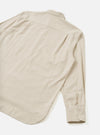 Flat lay of an ecru brushed flannel shirt showing the back view. The soft, lightly textured flannel fabric has a subtle melt. A point collar is visible at the top. One long sleeve extends to the lower right, with a buttoned cuff fastened with two buttons. Shot on a white studio backdrop.