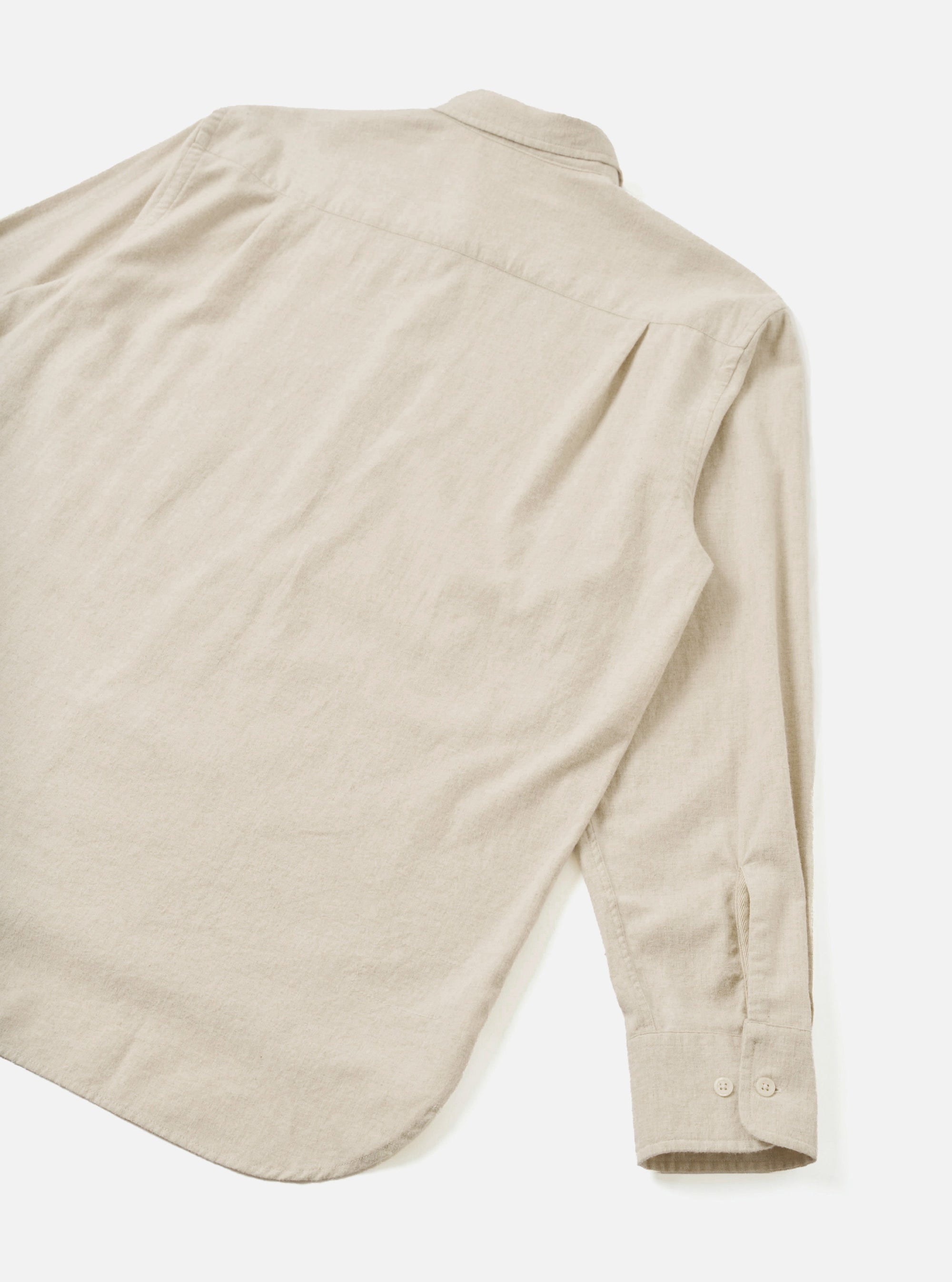 Flat lay of an ecru brushed flannel shirt showing the back view. The soft, lightly textured flannel fabric has a subtle melt. A point collar is visible at the top. One long sleeve extends to the lower right, with a buttoned cuff fastened with two buttons. Shot on a white studio backdrop.