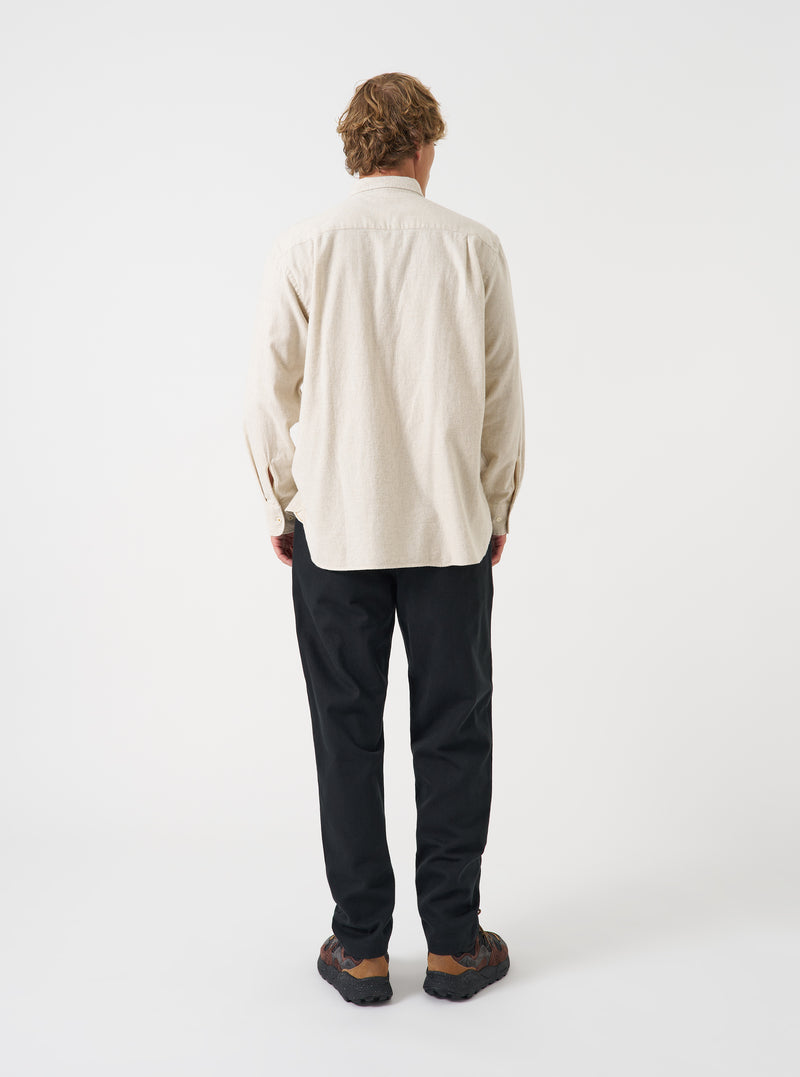 A male model poses in a neutral studio background wearing the Ecru Brushed Flannel Square Pocket Shirt. The three-quarter shot showcases the soft fabric texture, relaxed fit, and sleeve button details.
