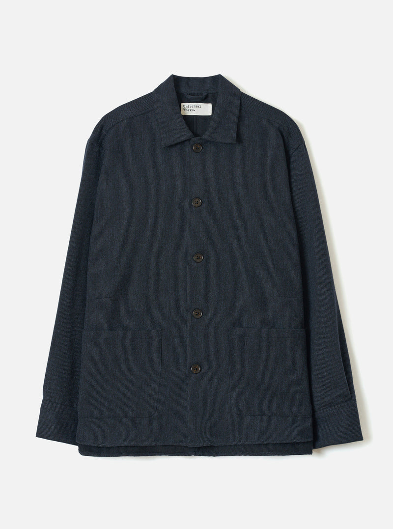 Navy flannel overshirt in a fine stripe texture, laid flat on a white studio backdrop. Features a spread collar with a Universal Works woven label, five dark buttons down the centre front, two large patch pockets at the hip, and wide cuffed sleeves.