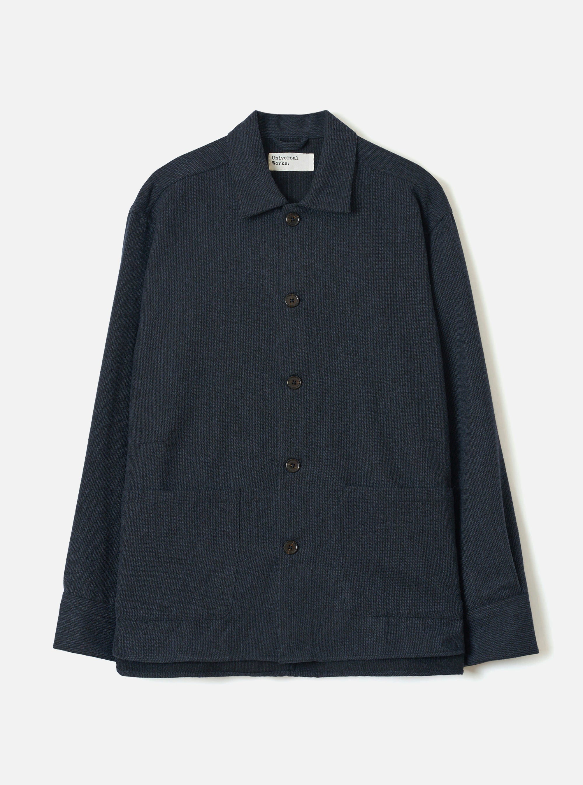 Navy flannel overshirt in a fine stripe texture, laid flat on a white studio backdrop. Features a spread collar with a Universal Works woven label, five dark buttons down the centre front, two large patch pockets at the hip, and wide cuffed sleeves.