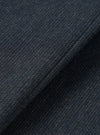 Close-up of the navy flannel fabric used in the Airline Travail Overshirt. The tight, nubby weave shows a dark navy base with flecks of grey and blue throughout, giving a heathered, textured appearance. A diagonal fold runs across the frame, highlighting the fabric's soft, lightly brushed surface.