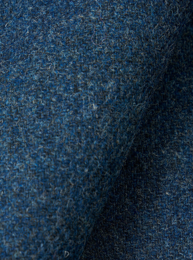 A close-up fabric swatch displaying the intricate weave and tactile surface of the Blue Harris Tweed Easy Jacket. The detailed image fills the frame to highlight the multi-tonal blue wool fibers.