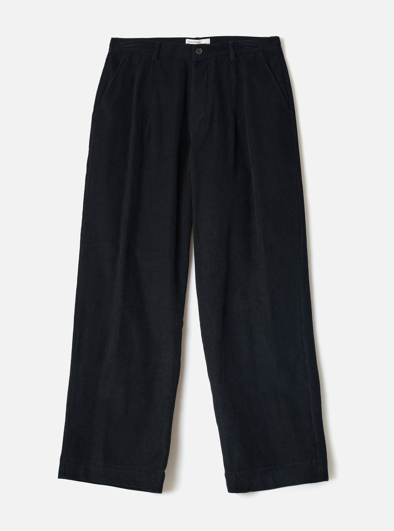Flat lay of black corduroy wide-leg chinos on a white studio backdrop. The ribbed cord texture is visible across the full length. Features a single button fly, front pleats, slant side pockets, belt loops, and a straight wide hem. A small branded label sits at the inner waistband.
