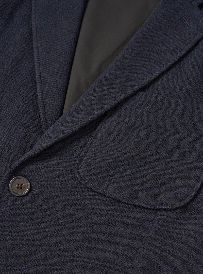 A male model wears the Dark Navy Robin Wool Mix Two Button Jacket styled over a casual outfit against a plain light studio backdrop, demonstrating the relaxed tailor fit, wide lapels, and patch pockets.