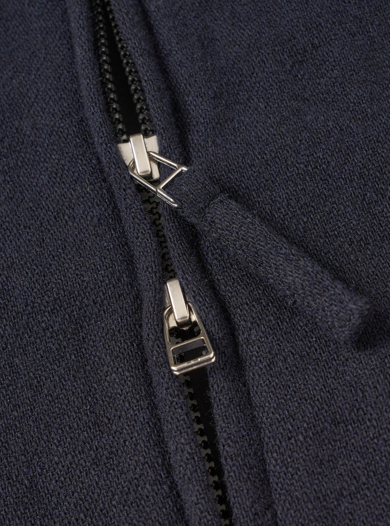 A male model wears the Dark Navy Robin Wool Mix Club Jacket zipped up, standing against a neutral studio backdrop, illustrating the jacket's loose fit, adjustable hem, and smart-casual aesthetic.
