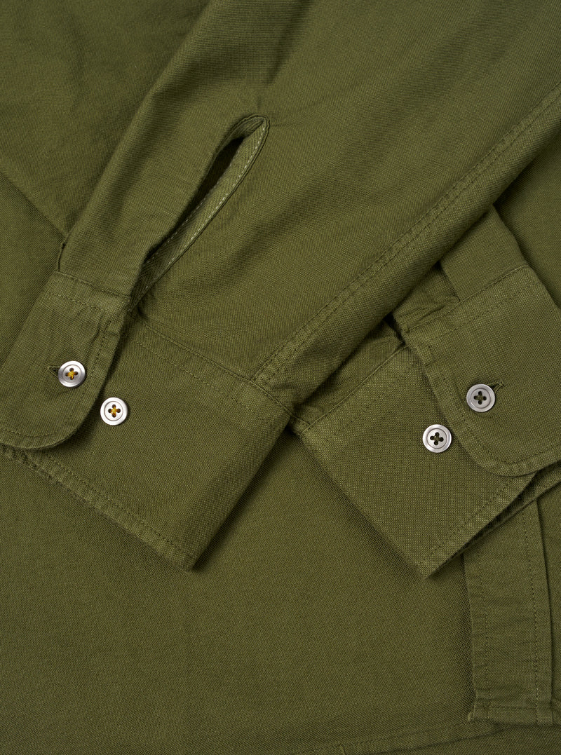 A male model wears the Olive R.Oxford Lazy Day Shirt unbuttoned over a neutral tee, standing against a plain studio backdrop to display the shirt's relaxed silhouette and drape.